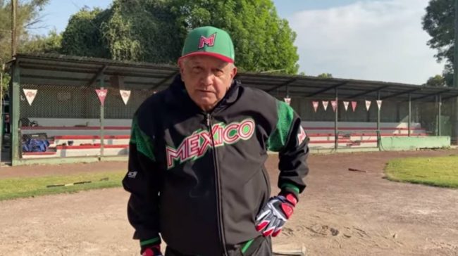 Andrés Manuel López Obrador con chamarra de México y gorra en campo de béisbol