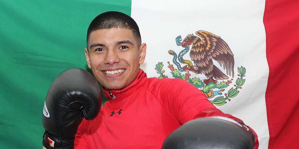 Joselito Velázquez con bandera de México detrás suyo