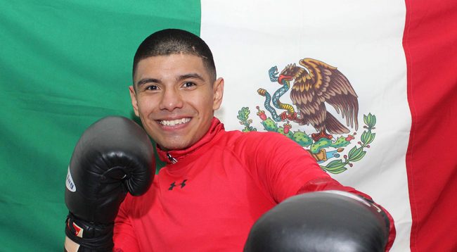Joselito Velázquez con bandera de México detrás suyo
